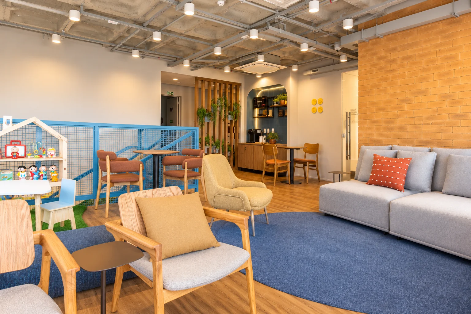 Área de espera com poltronas, sofá e espaço infantil ao fundo.